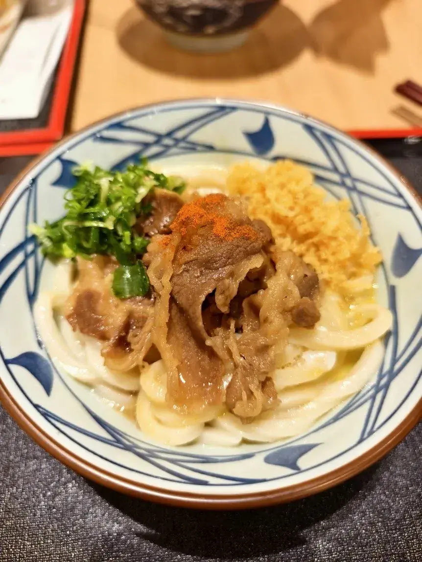 | 丸龜製麵牛肉烏龍麵實拍，搭配免費蔥花與天婦羅花